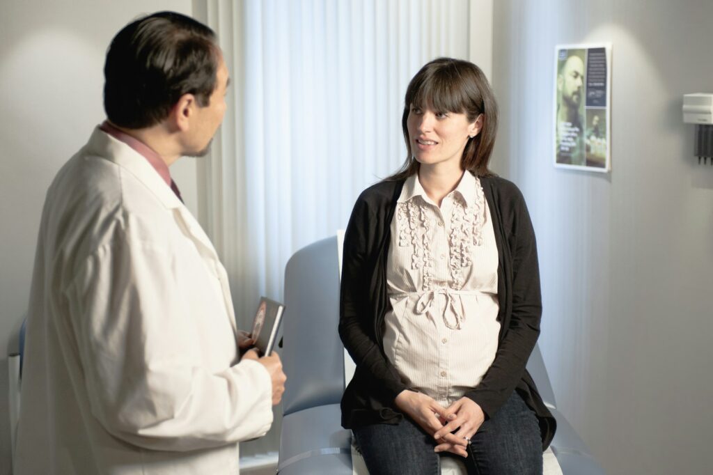 a doctor talking to a pregnant woman in a waiting room