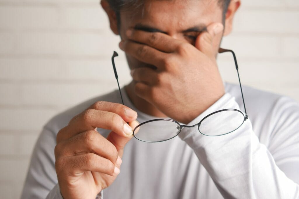 a man holding a pair of glasses up to his face