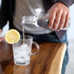 man pouring water in glass