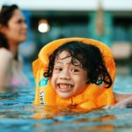 girl in white tank top on swimming pool during daytime