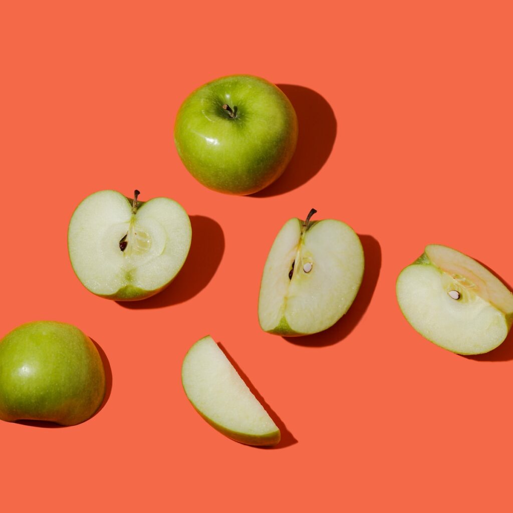 green apple fruit on pink surface