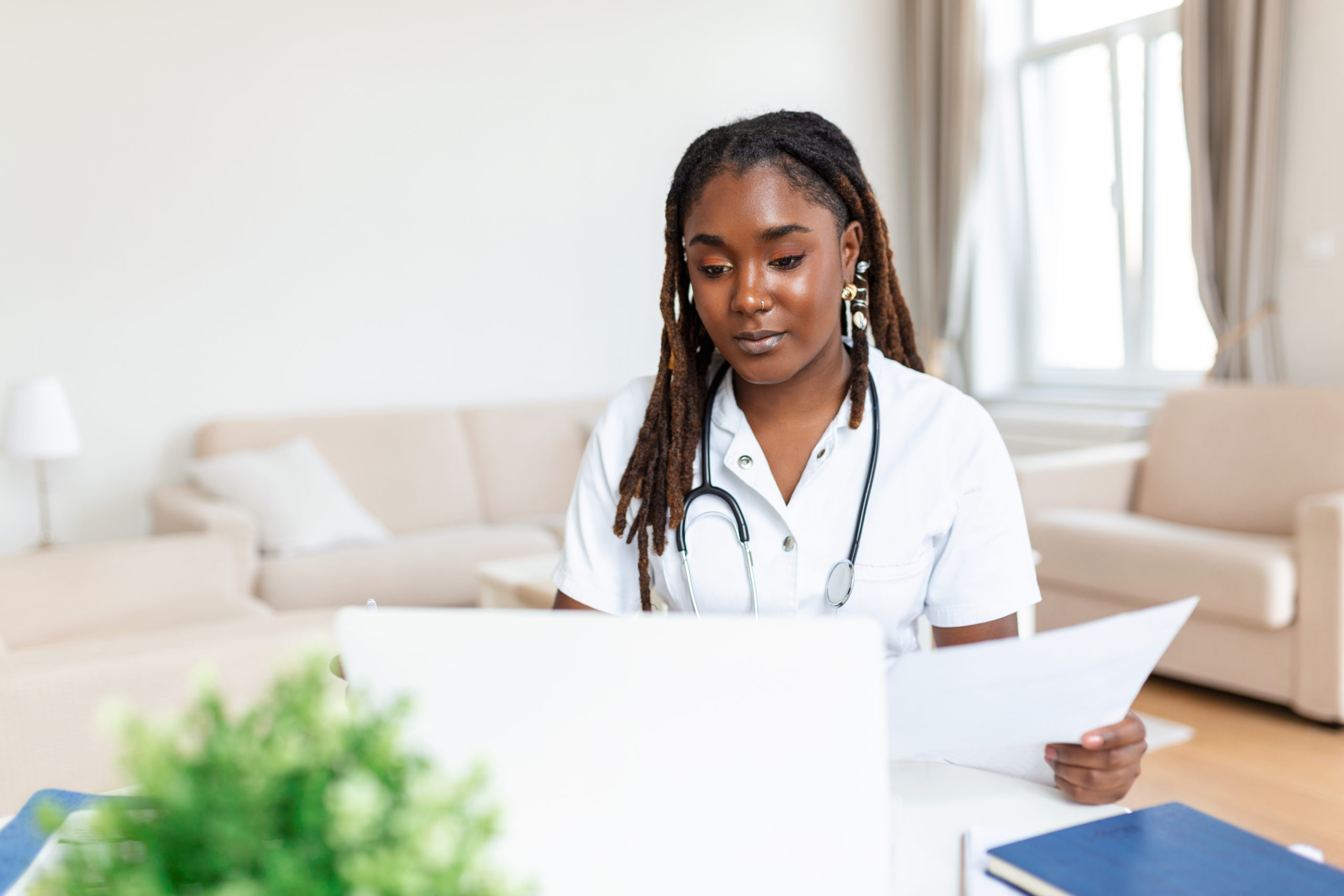 African oman doctor talking online with patient, making video call, looking at camera, young female wearing white uniform with stethoscope speaking, consulting and therapy concept