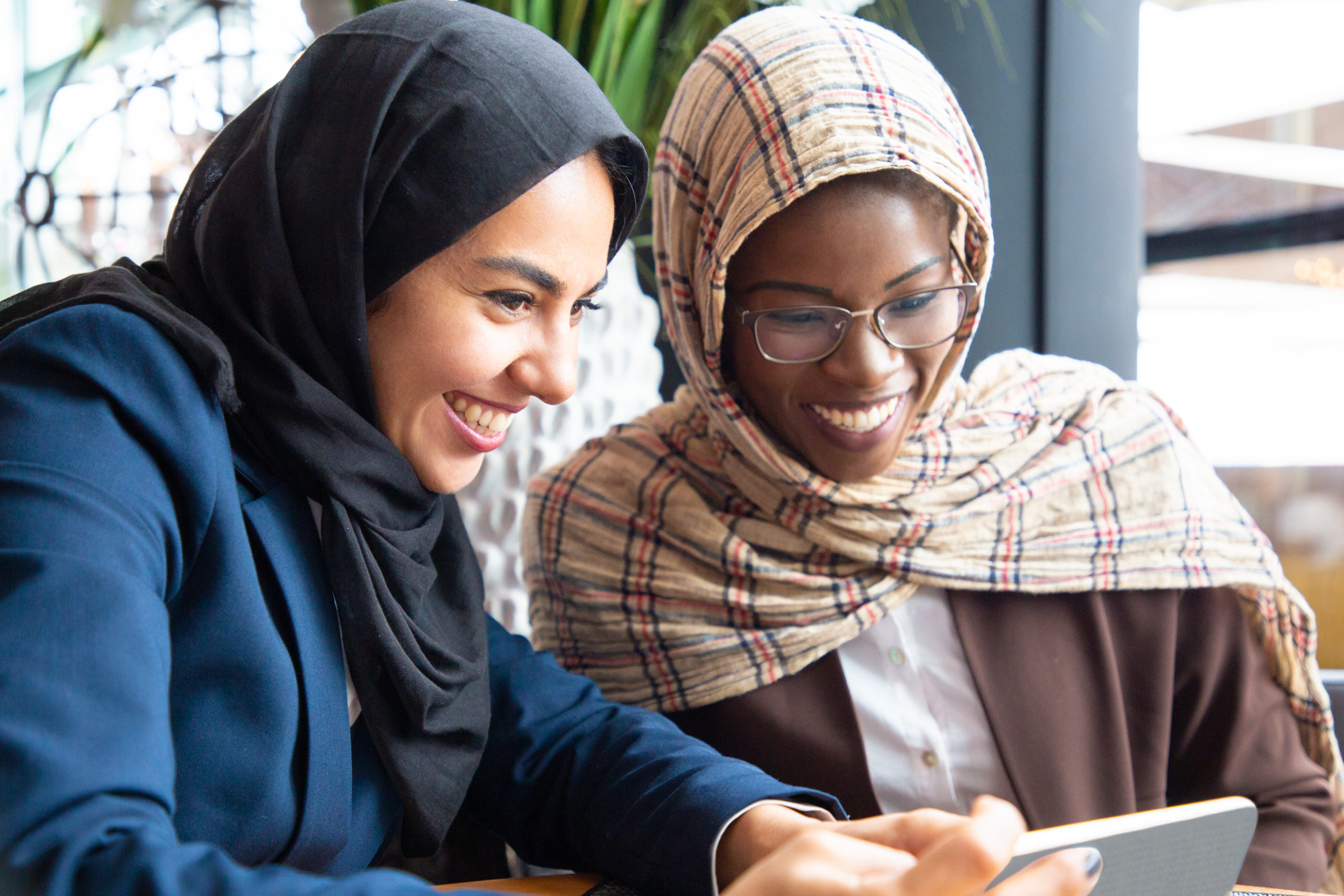 Joyful female colleagues watching content on phone