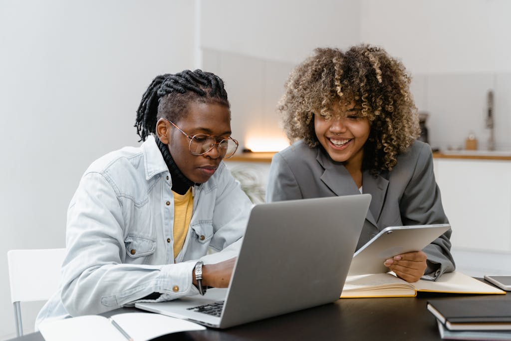 A Man and Woman Having Conversation while Sitting Near the Table with Laptop