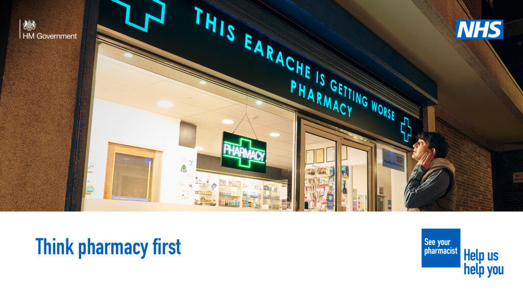 Image of a man outside a pharmacy holding his ear. He looks up at a an illuminated sign with the words "This earache is getting worse - PHARMCY". The poster also has wording saying "Think pharmacy first".