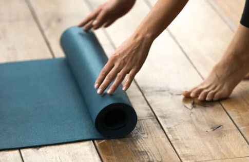 picture of someone rolling out a pilates exercise mat.