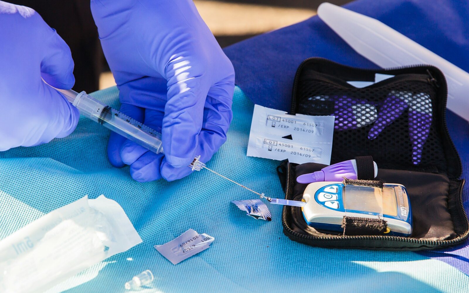 person using disposable syringe put specimen on blue and white glucose meter