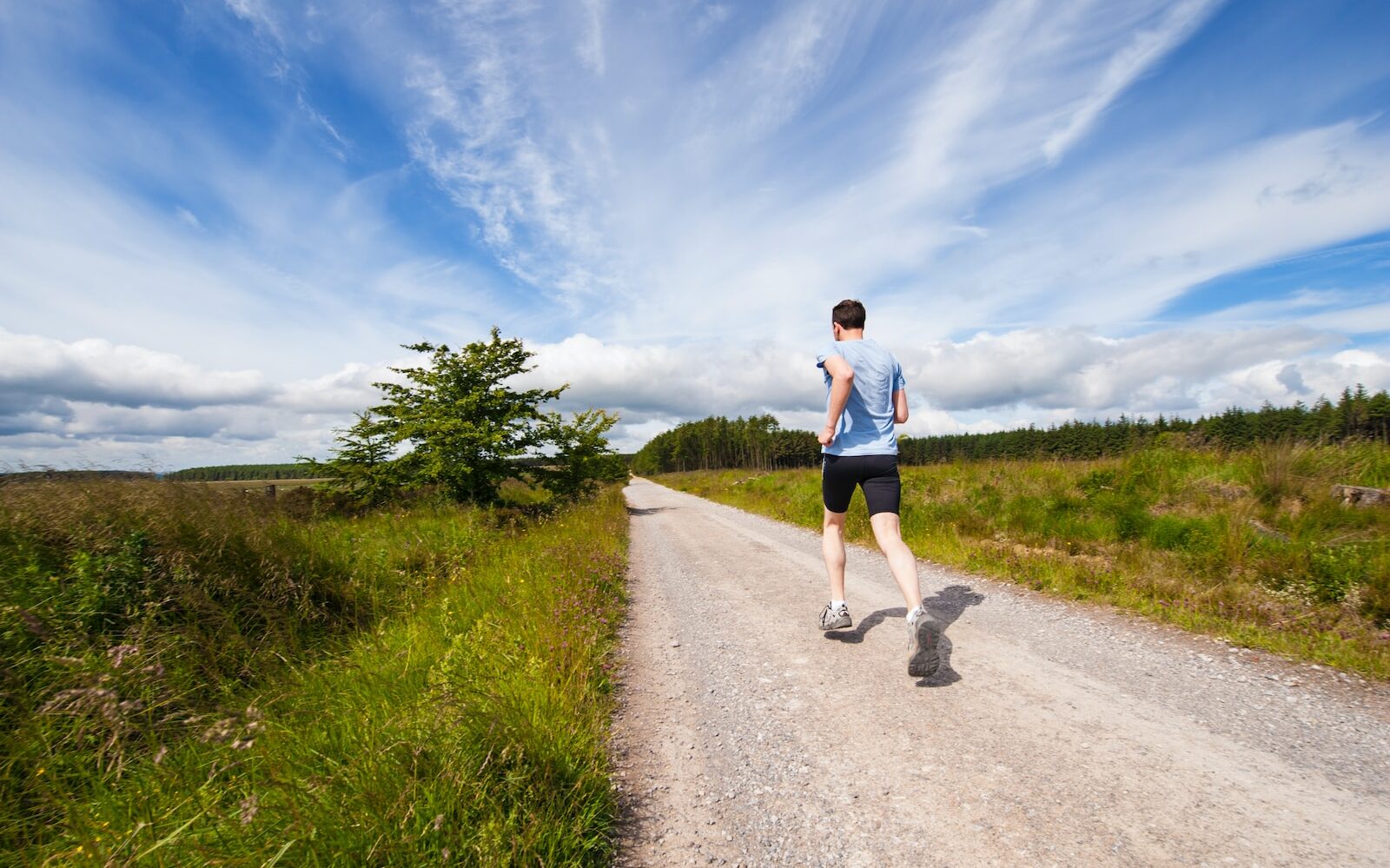 man running on road near grass field