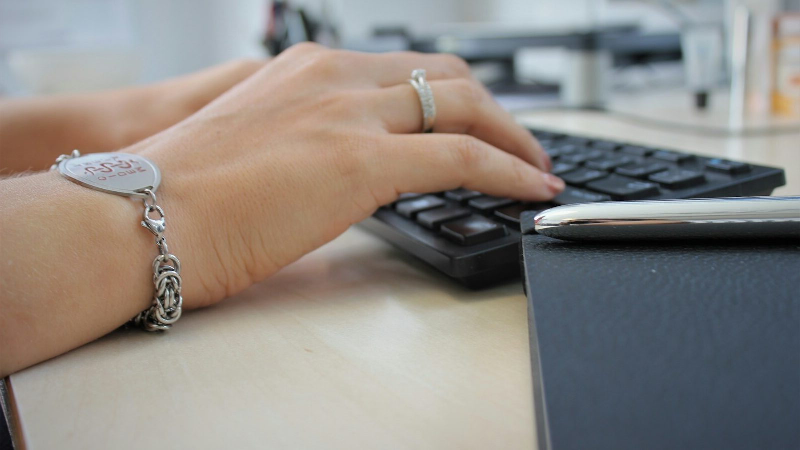 person wearing silver ring using black computer keyboard