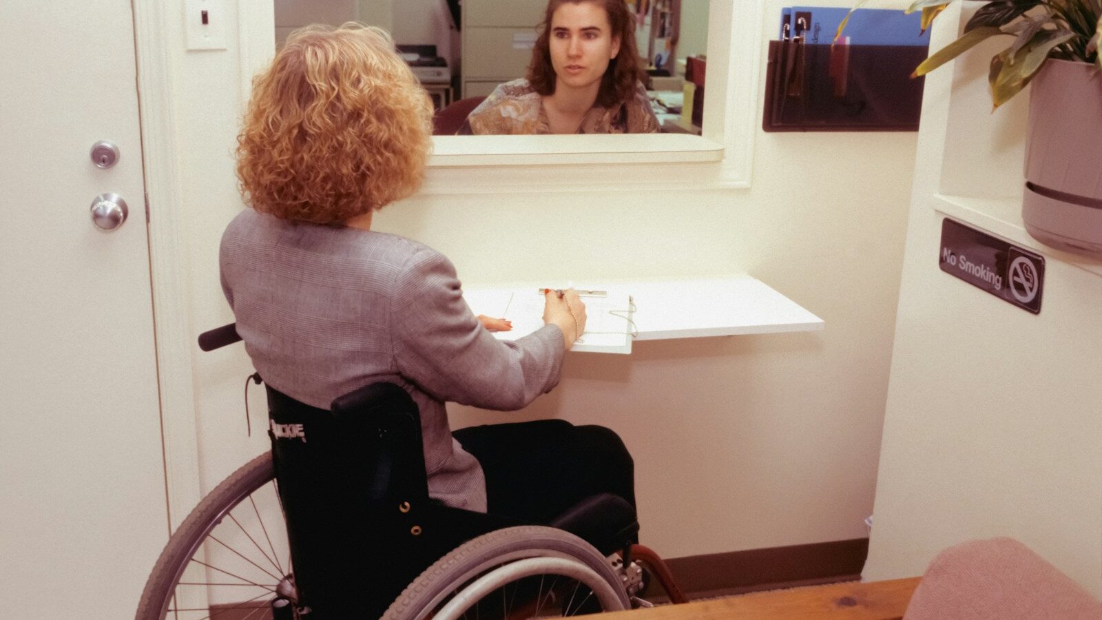 a woman sitting in a wheel chair in front of a mirror