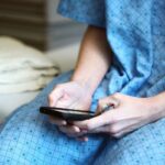 person in blue and white checkered button up shirt holding black smartphone