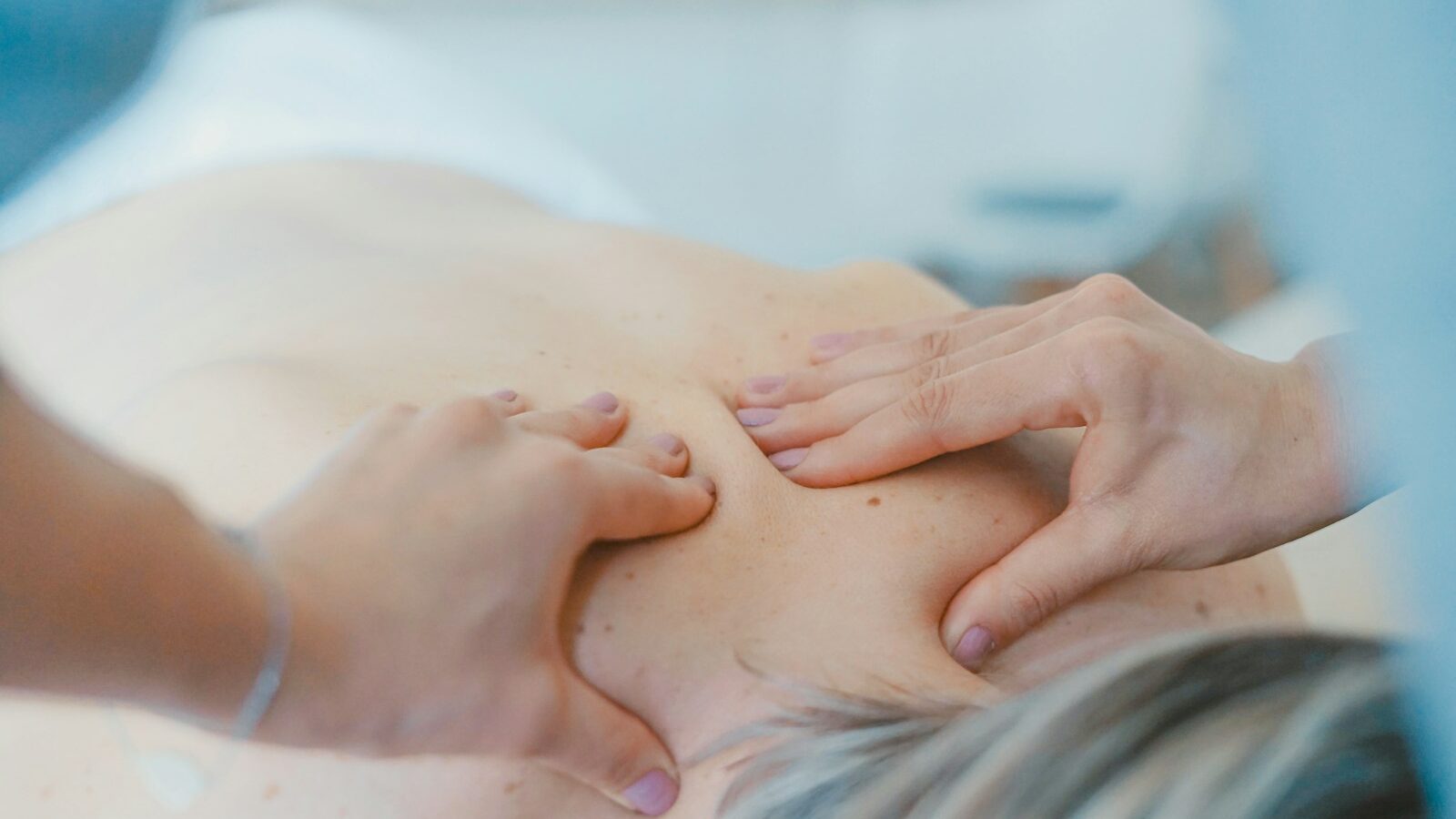 person massaging the back of a woman