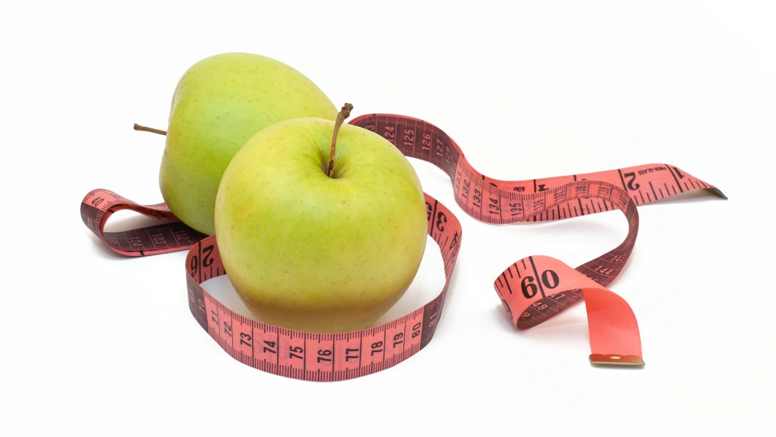 two green apples with a measuring tape around them