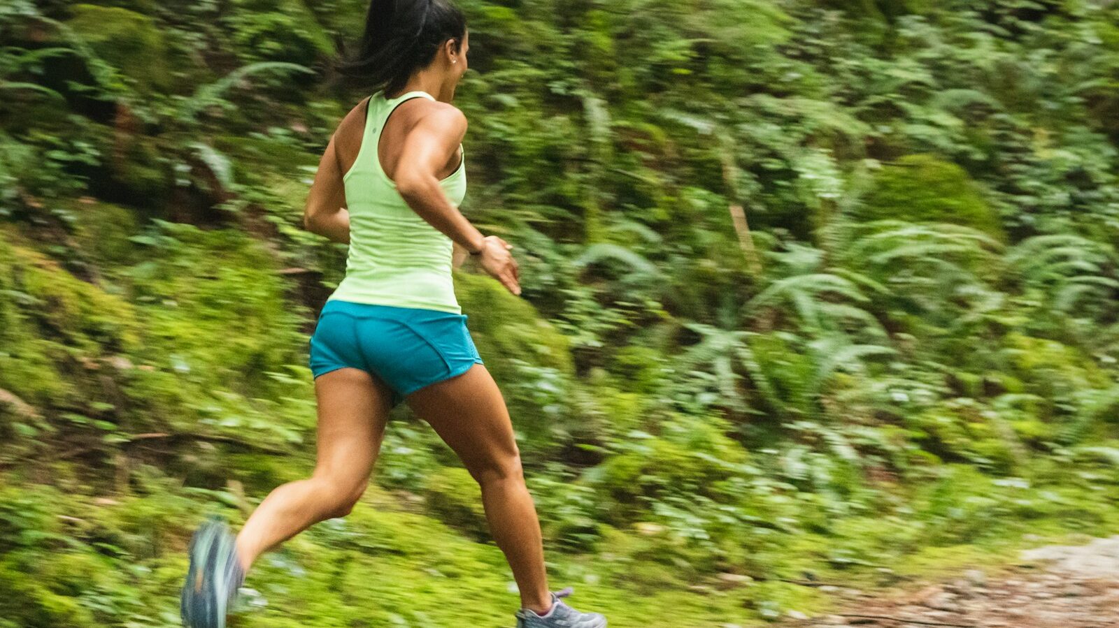 woman in white tank top running on dirt road during daytime