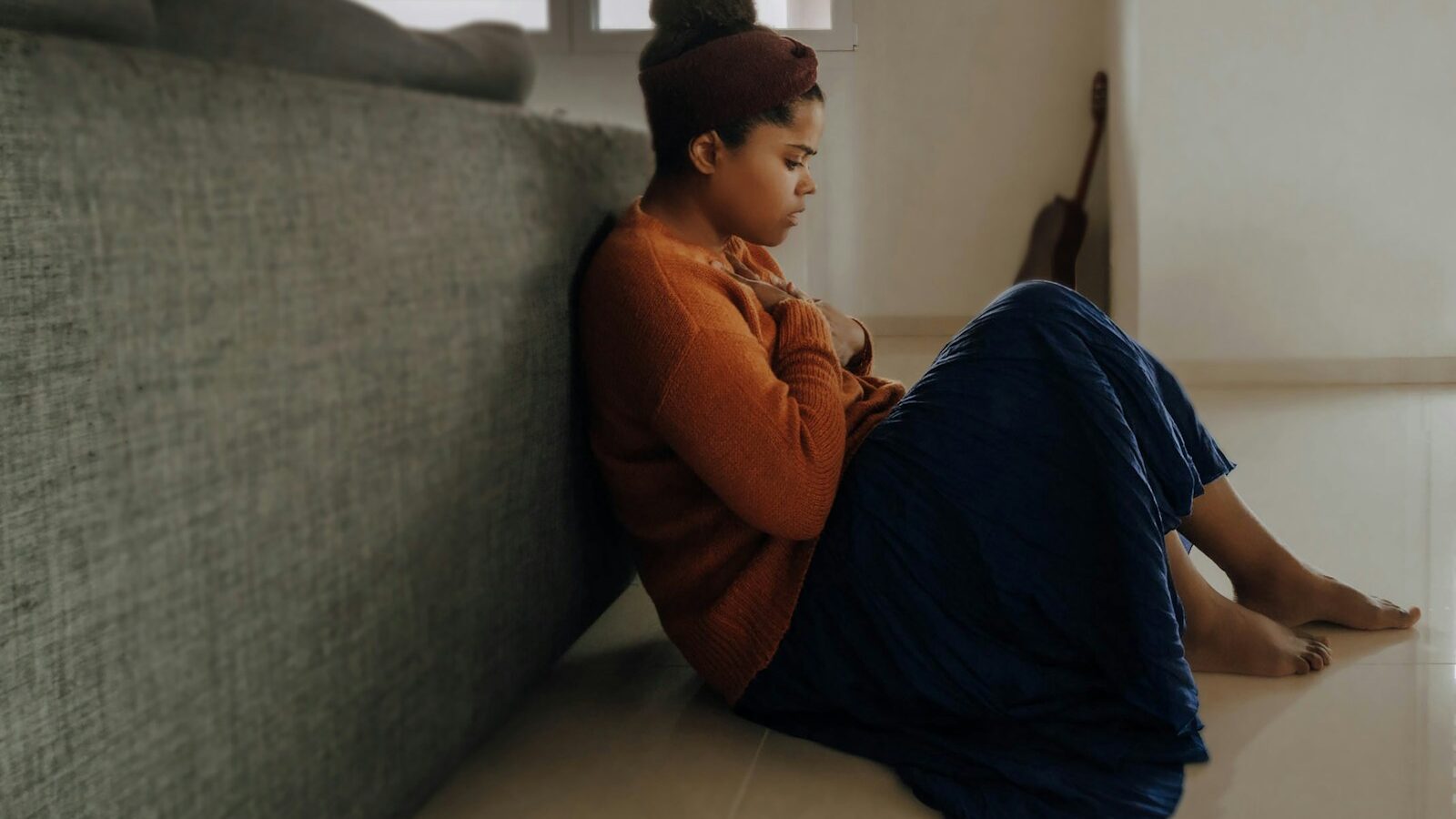 man in orange long sleeve shirt sitting on gray couch