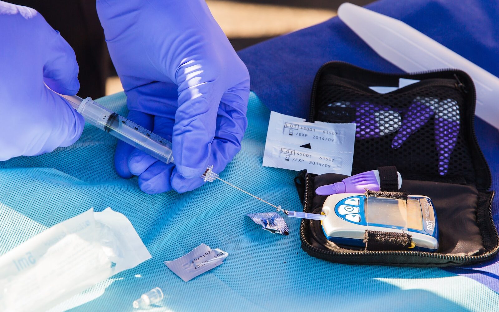 person using disposable syringe put specimen on blue and white glucose meter