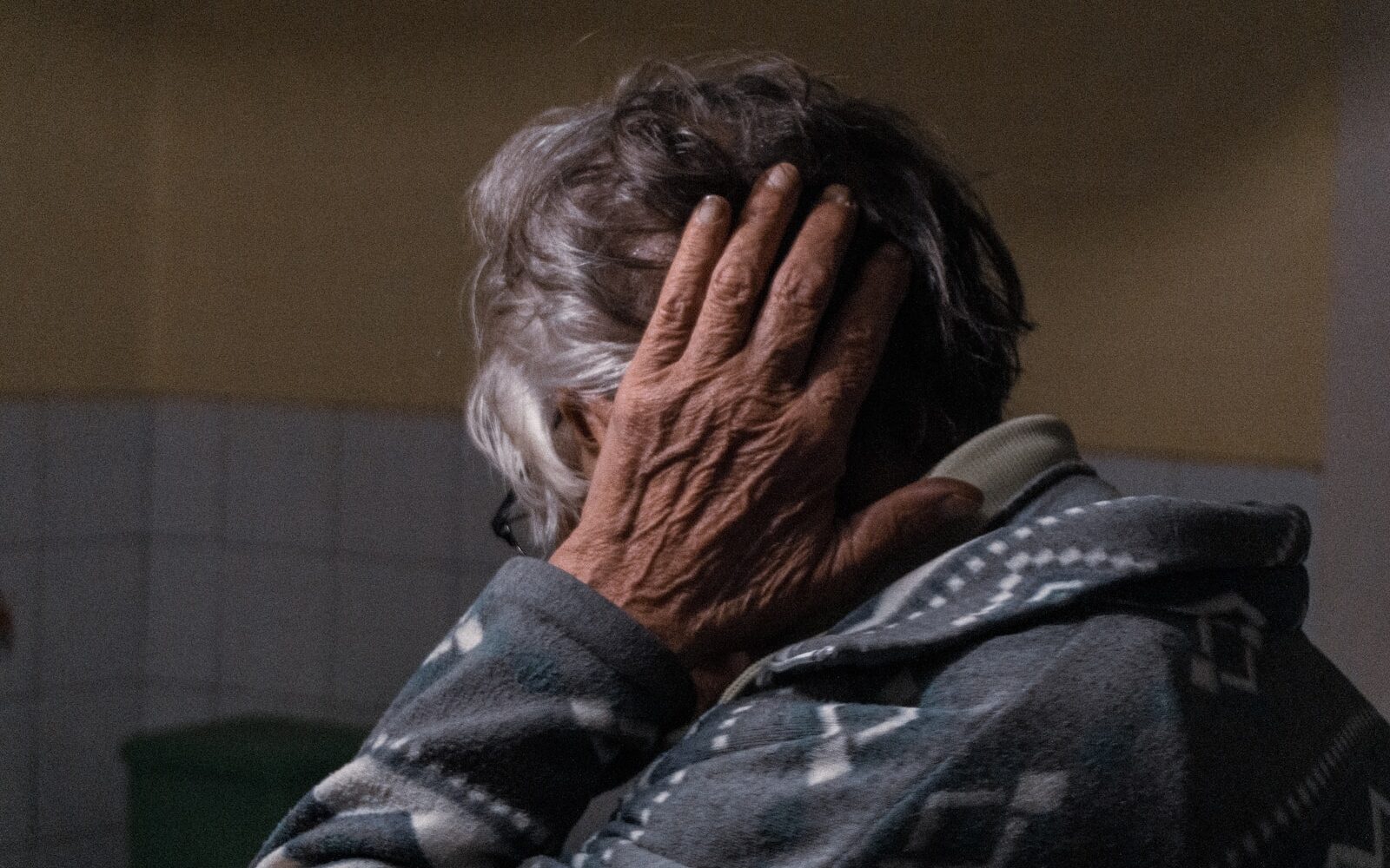 an older woman covering her face with her hands