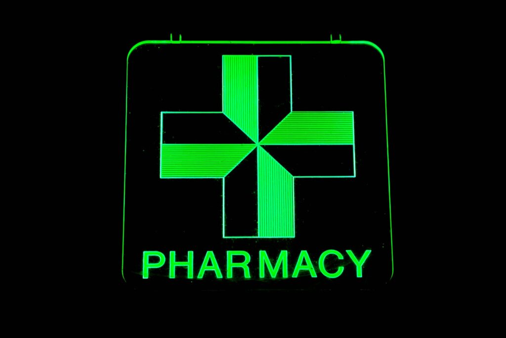 a green pharmacy sign with a cross on it