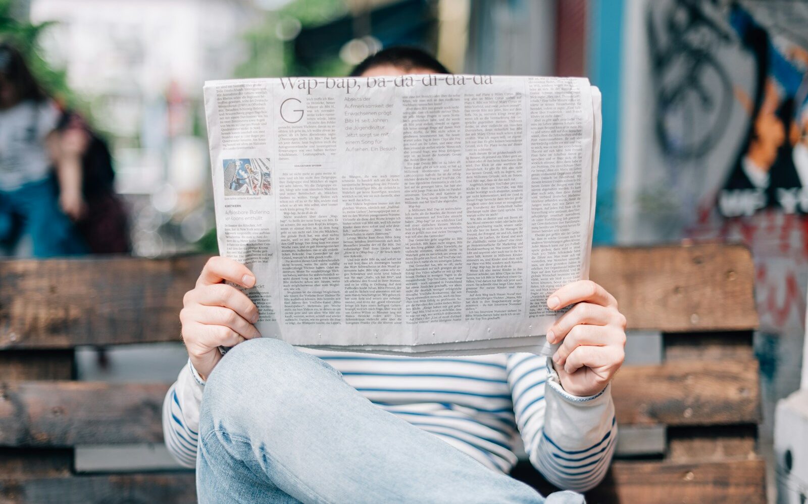 man sitting on bench reading newspaper