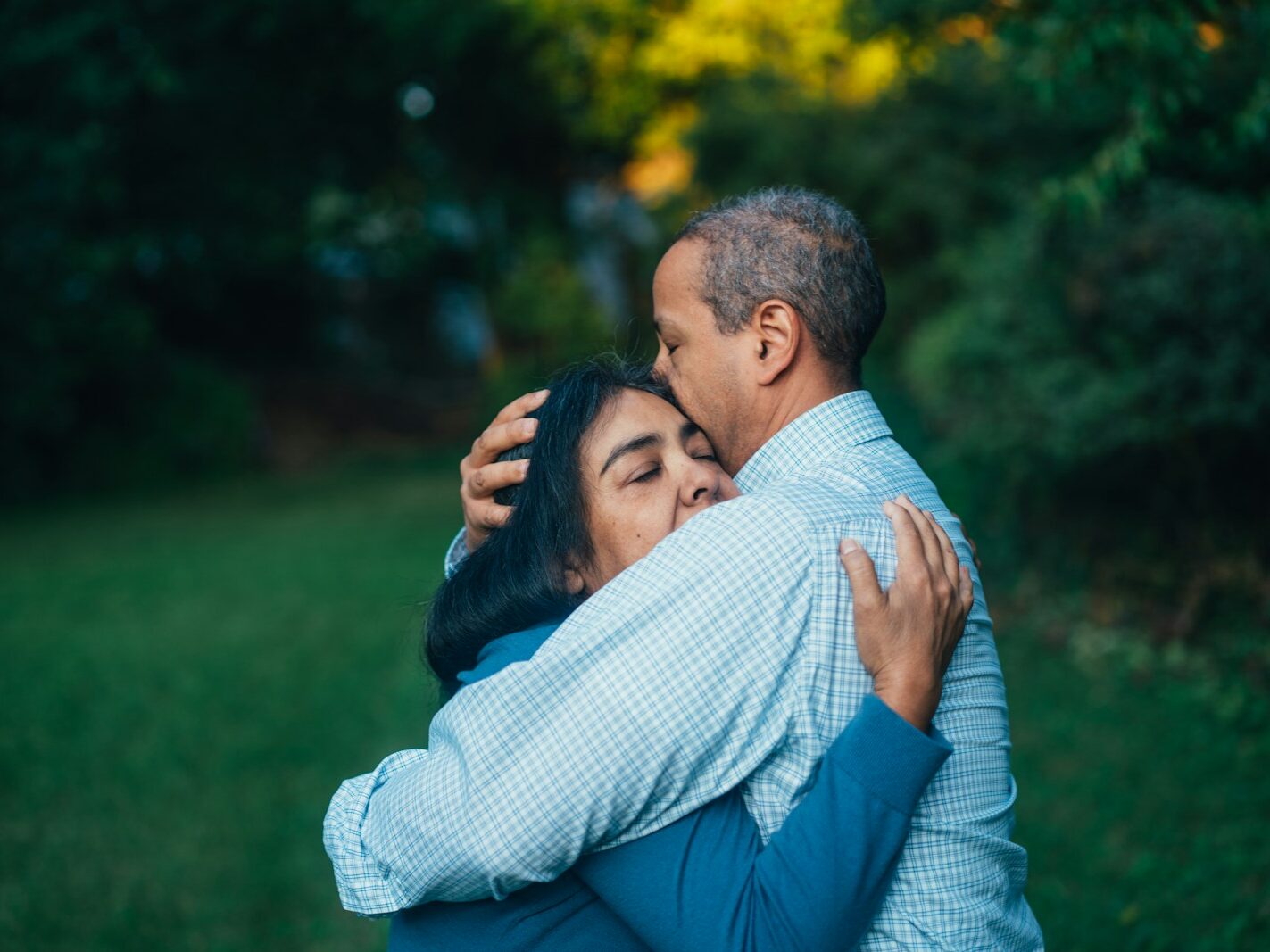 man hugging woman near trees