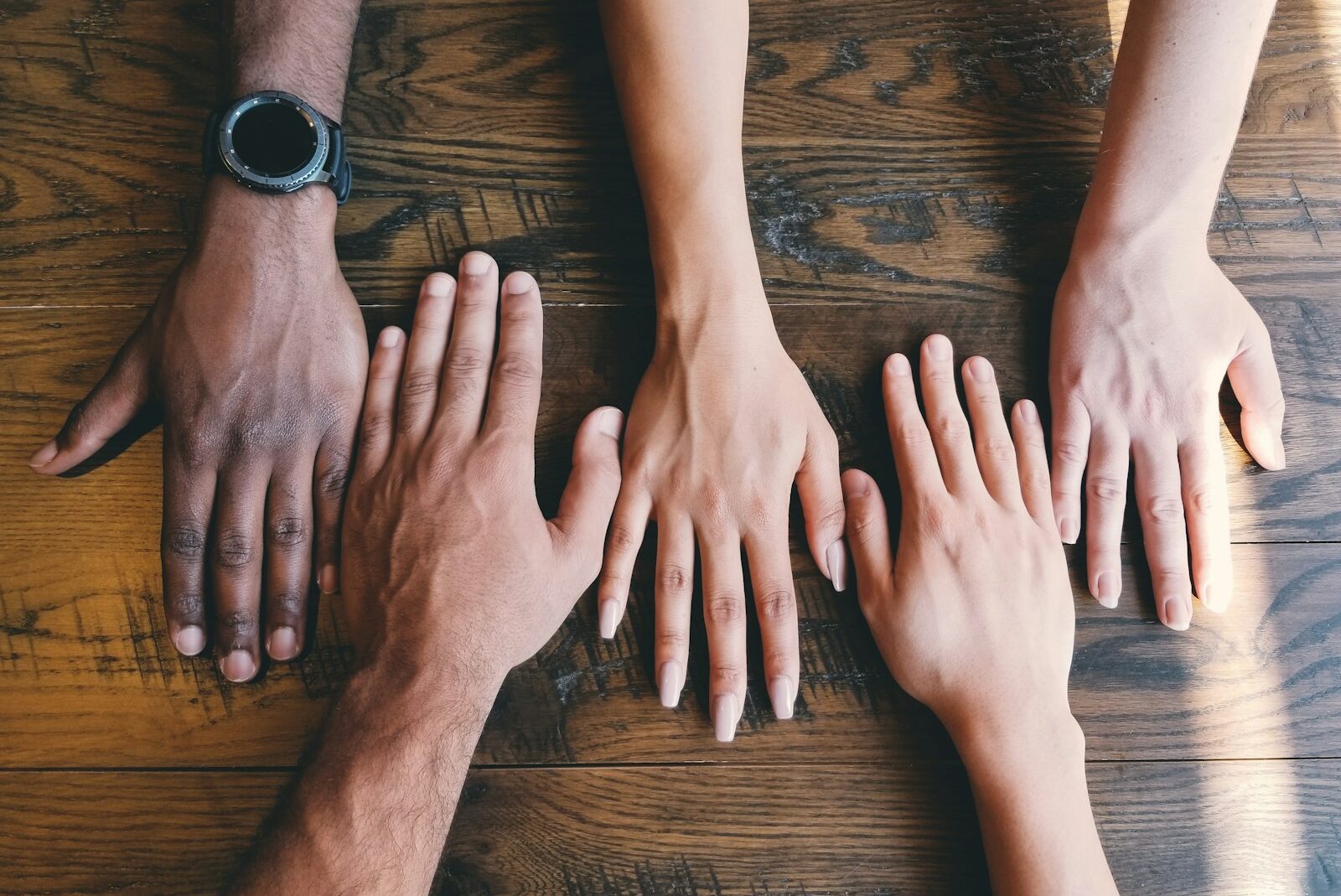 five human hands on brown surface