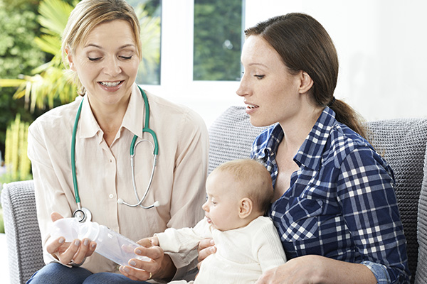 Health Visitor Giving Mother Advice On Feeding Baby With Bottle