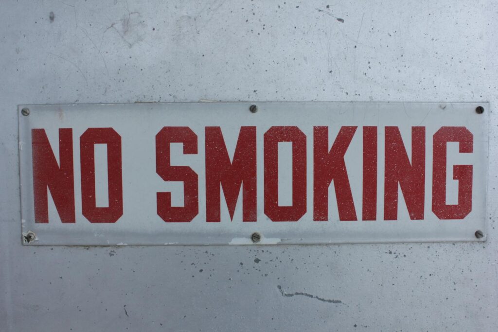 Close-up of a bold 'No Smoking' sign on a textured wall.