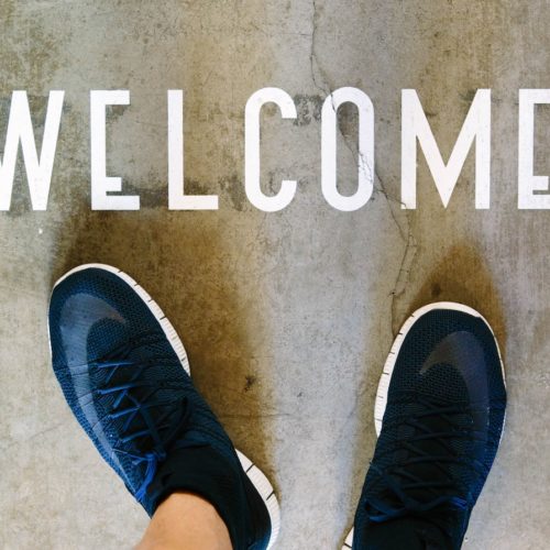 A person's feet in front of a welcome sign.