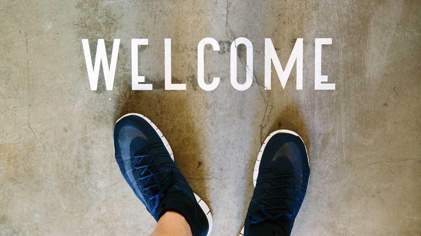 A person's feet in front of a welcome sign.