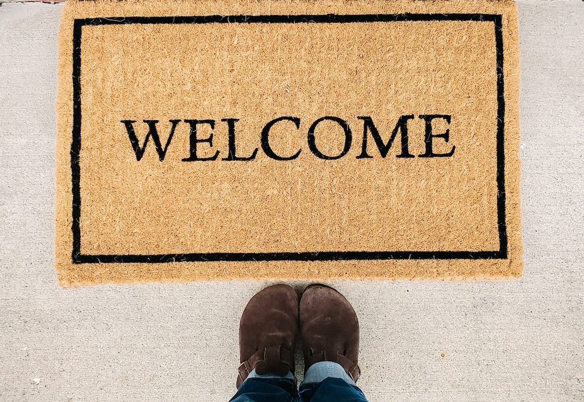 person in blue denim jeans standing on brown and black welcome area rug