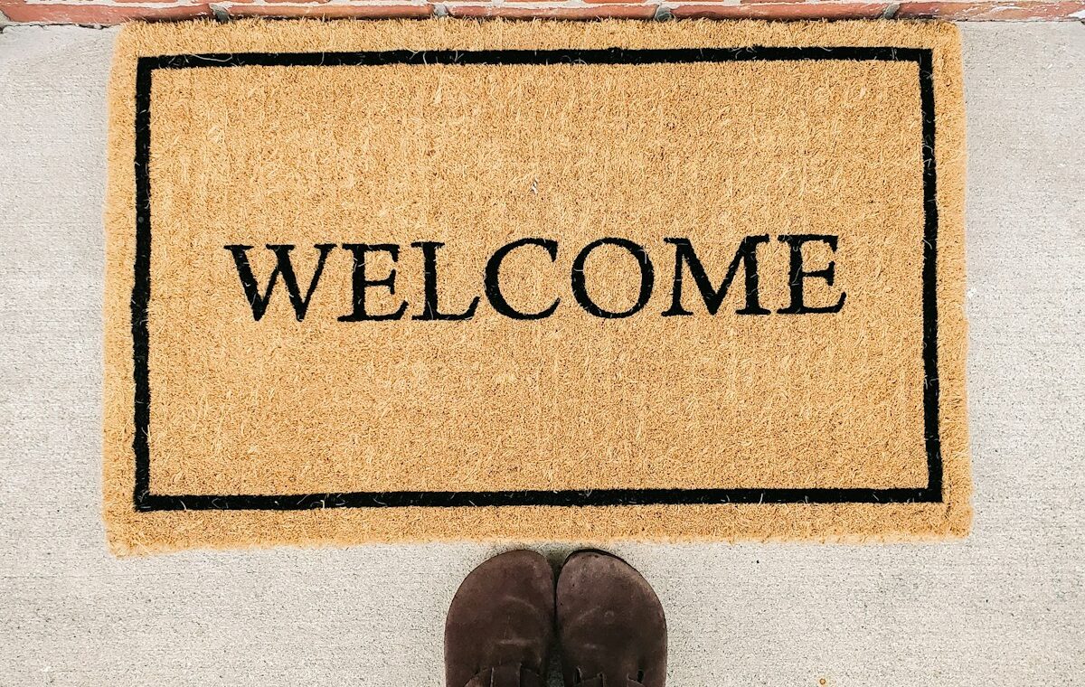 person in blue denim jeans standing on brown and black welcome area rug