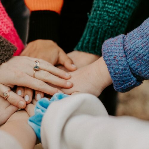 person in red sweater holding babys hand