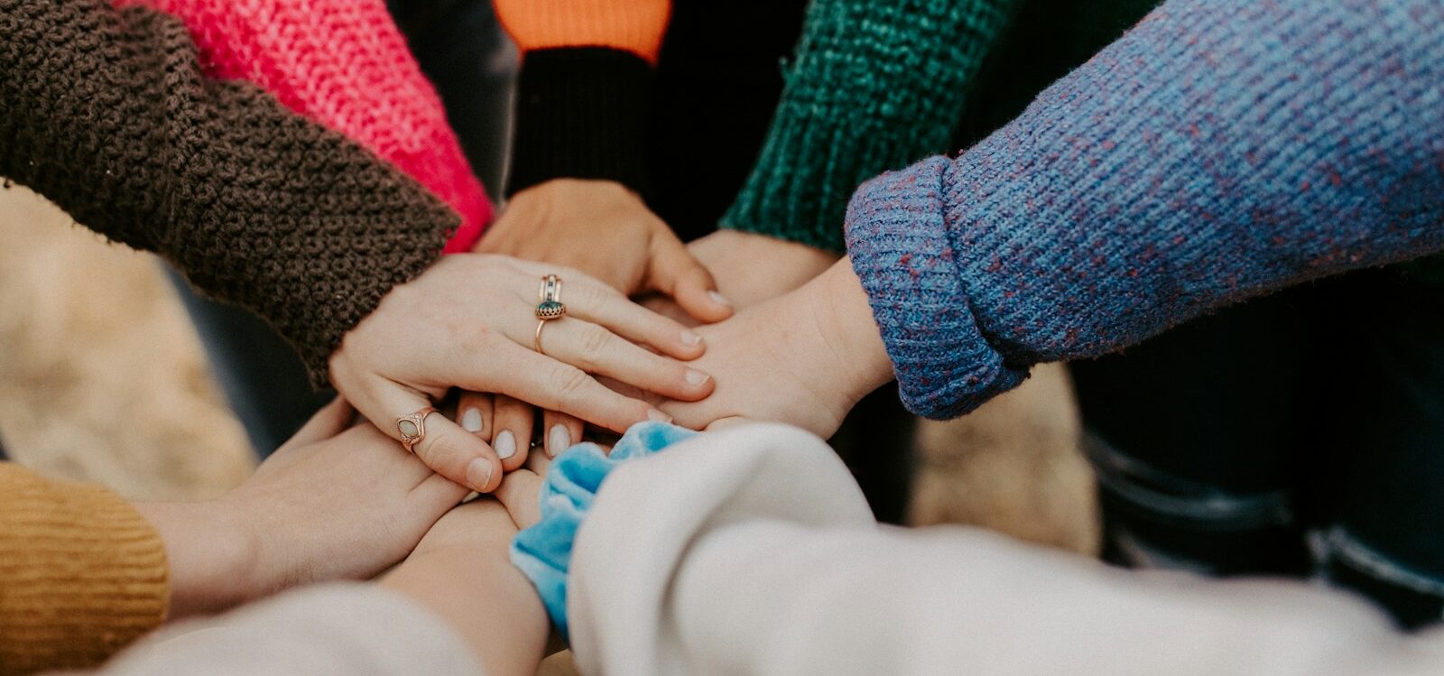 person in red sweater holding babys hand