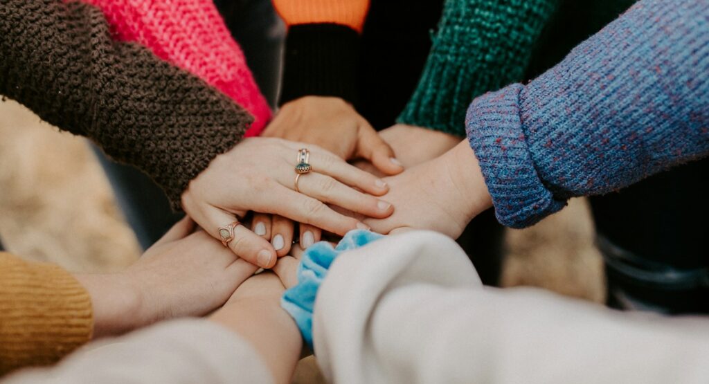 person in red sweater holding babys hand