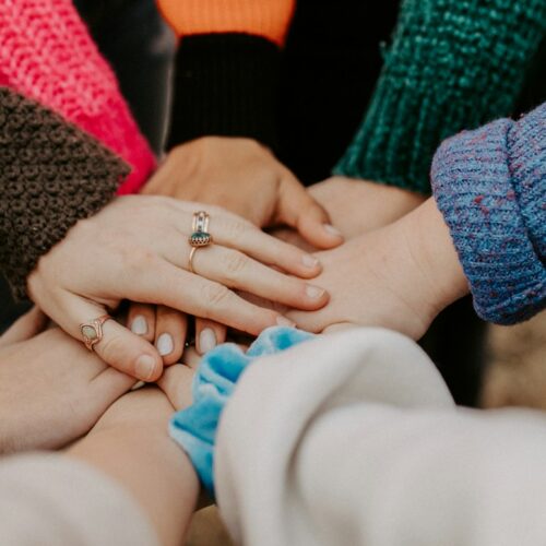 person in red sweater holding babys hand