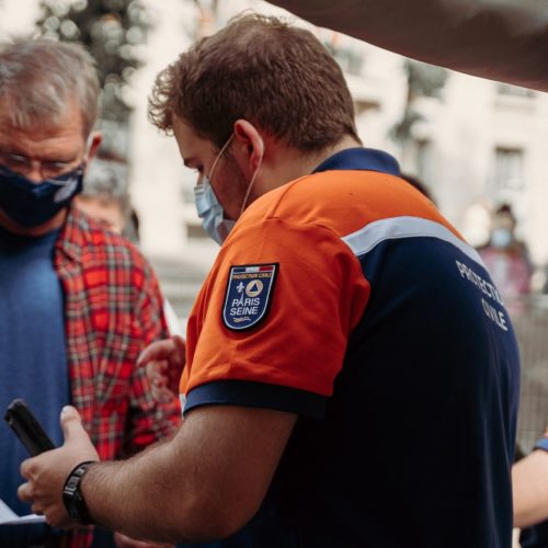 man in blue and orange polo shirt holding black smartphone