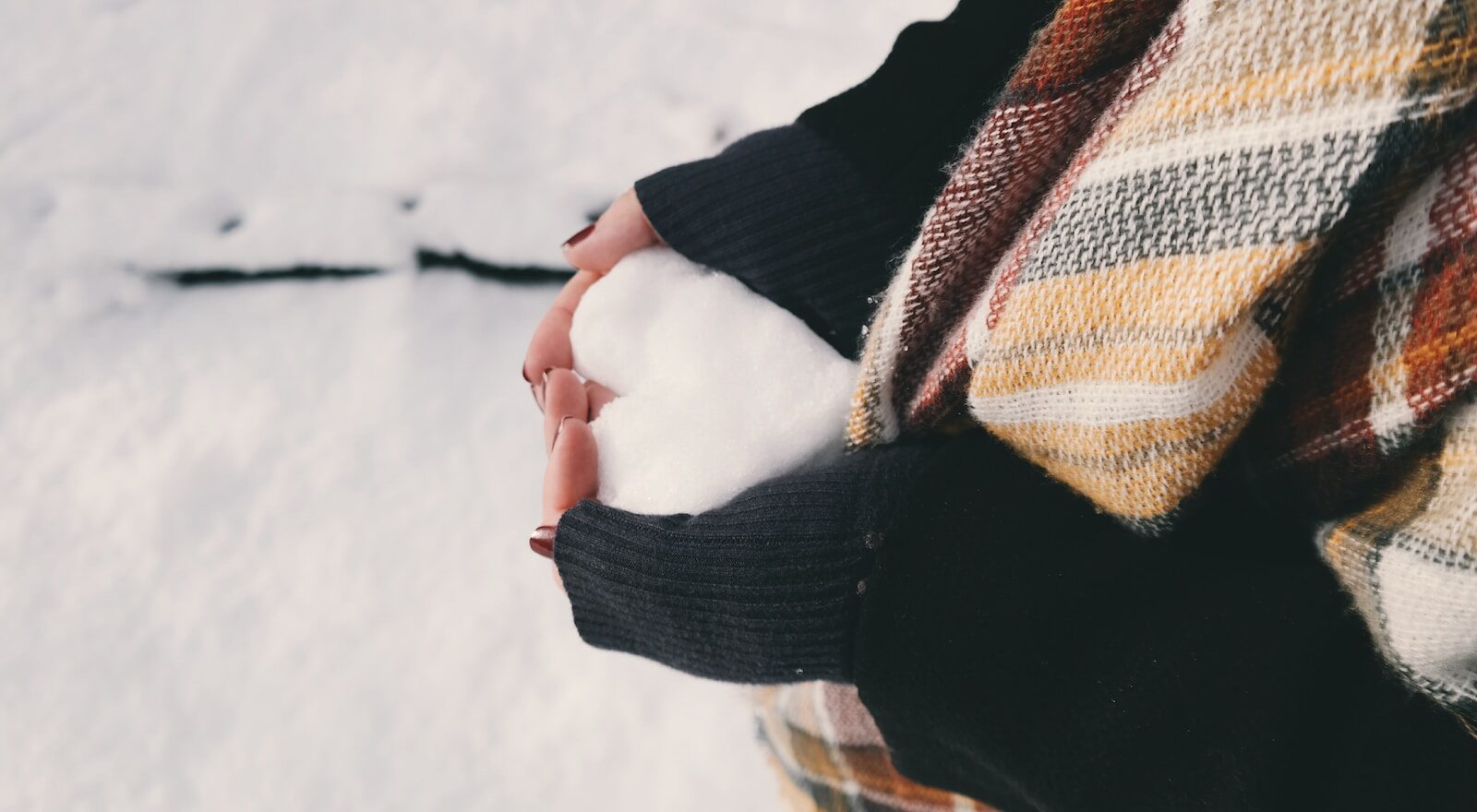 woman wearing black sweater holding ice forming heart