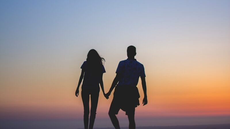 man and woman holding hands in silhouette photography